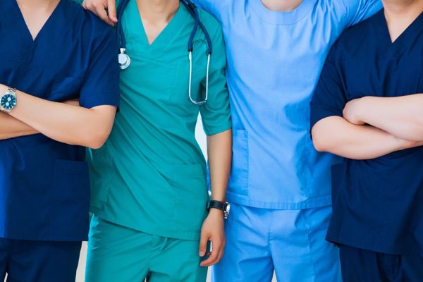 A group of 4 doctors wearing different colors of medical scrubs showcasing medical dress codes